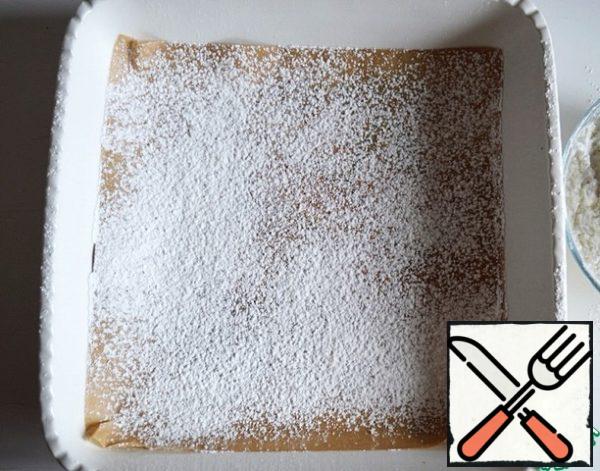 Cover a 20 * 20 square shape with baking paper and sprinkle with a thin layer of a mixture of powdered sugar and corn starch.
