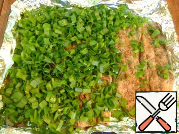 Preheat the oven to 180 degrees. Cut green onions into rings. Cover the baking sheet with foil, grease with vegetable oil. Place the mackerel fillets on a baking sheet and cover with a layer of green onions.
