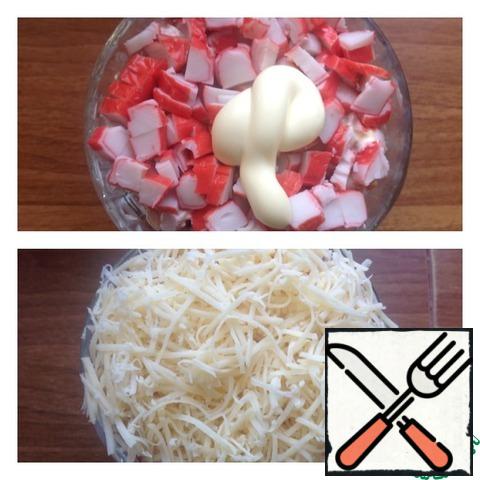 Next, a layer of crab sticks cut into a small cube and grease with mayonnaise. Cheese grate on a fine grater. This is our final layer.
