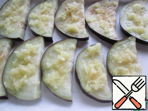 Grease the baking paper with vegetable oil, place on a baking sheet and put the eggplant slices on it. Lightly grease with a brush each with vegetable oil and put chopped up garlic.
Put in a preheated oven (180 degrees) for 30 minutes.