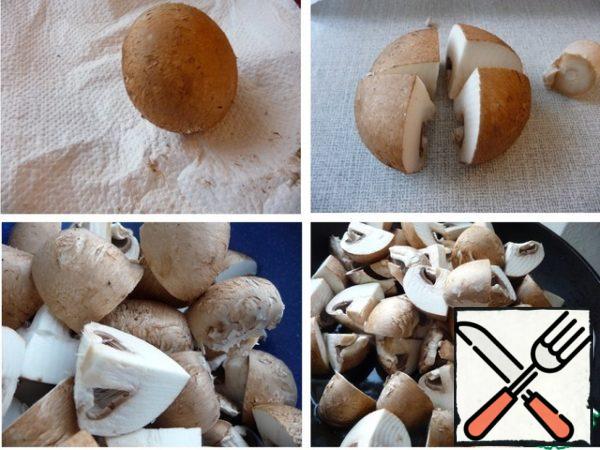 Mushrooms are not washed, the film is not removed.
Clean the mushrooms with a paper napkin. Cut the legs (I used them in the soup).
Cut the large one into four parts, the small one in half.
Fry the mushrooms in preheated vegetable oil for about 4-5 minutes.
stirring constantly.