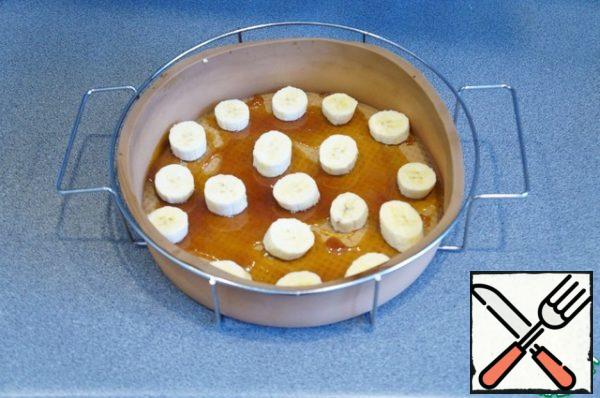 Pour the caramel into the form, spread the pieces of 2 bananas on top.
