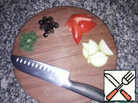 Cut vegetables. Zucchini-slices, pepper-slices, olives-rings, finely chop the greens.