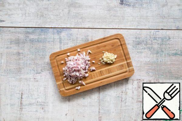 Chop the shallots and garlic very finely. In a deep frying pan, melt the butter, lay out the chicken breasts and fry quickly on high heat on all sides. Transfer the meat to a plate.
