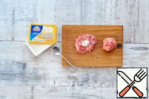Cover the baking sheet with baking paper. Lubricate your hands with olive oil and roll the same meatballs out of minced meat the size of a large walnut with cheese inside: first make a flatbread out of minced meat, put half a spoonful of cheese inside, connect the edges and gently roll into a ball.
