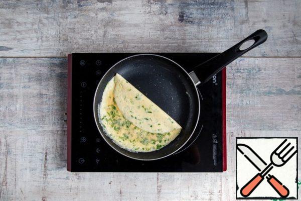 Without removing from the heat, tilt the pan so that most of the egg mass moves to the bottom of the pan. Carefully prying a thin egg film, wrap half of the omelet in it.
