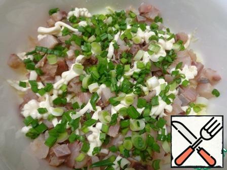 The second layer-herring, which cover with mayonnaise and green onions.