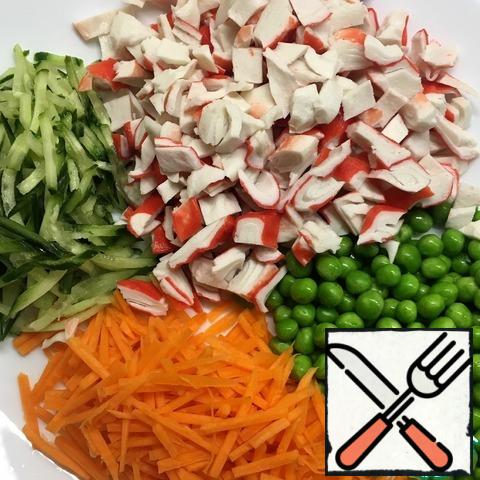 Carrots and zucchini three on a Korean grater or cut into thin cubes.
Crab sticks cut into cubes. Defrost the peas and drain the resulting water.