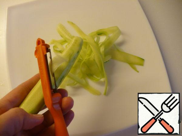 Cucumbers and carrots wash, peel and cut into transparent plates with a vegetable peeler along the length.