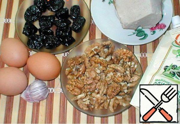 Prepare the ingredients for the recipe.Boil the eggs hard, separate the whites from the yolks.
Ham cut into thin strips.Prepare the dressing. To do this, mix the crushed garlic, nuts and prunes and mix with mayonnaise.