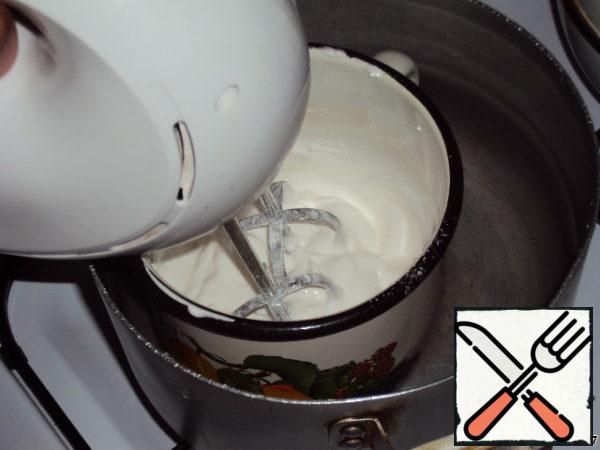 Prepare the meringue cream: beat the remaining 3 egg whites with 2 tablespoons of water, a packet of vanilla and powdered sugar in a water bath, at low speed for about 5 minutes, then at high speed for another 3-4 minutes. Remove from heat and whisk until the cream has cooled.