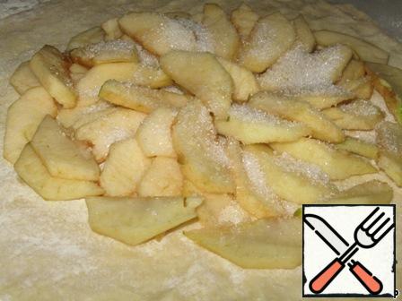 Roll the dough. I must warn you: working with him is not very fun. It sticks to your hands and is difficult to roll out. I'm doing this directly on the parchment paper. Peel the apples and cut into plates. Spread on the dough.