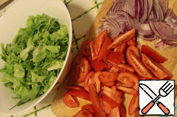 Tear the lettuce leaves with your hands, cut the tomatoes into thin slices, the onion into four parts and then as thin as possible.