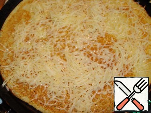 Fry on the one hand, turn over, sprinkle with 1-2 tablespoons of grated cheese.