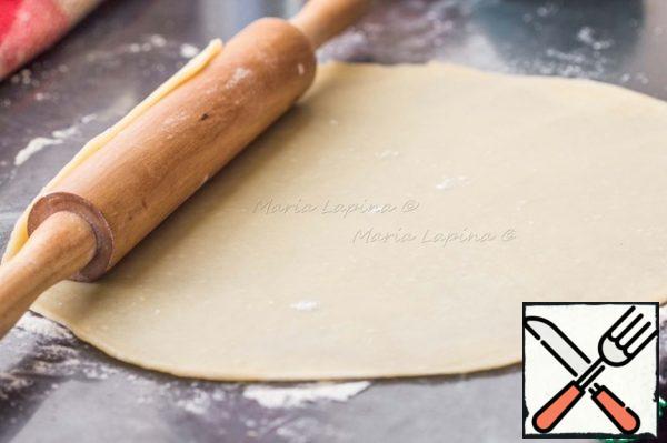 Roll out the dough with a thin round layer, transfer to a baking sheet with baking paper.