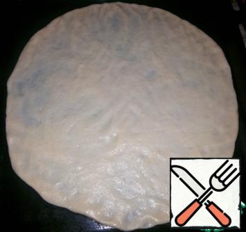 Half an hour passed.
Roll out the dough on a baking sheet (in the form of a circle with a diameter of 30-40cm approximately). There is no need to lubricate the baking sheet - there is enough oil in the dough.