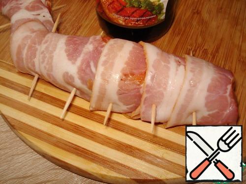 Each piece of fish wrapped in strips of bacon, fastened with toothpicks.