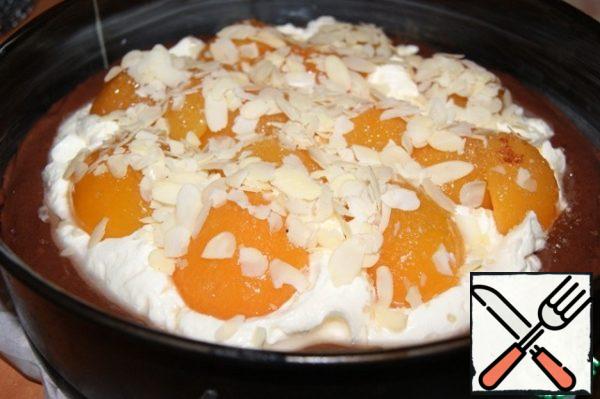 Place the dough in a form 23 cm in diameter, the bottom of which is covered with baking paper, and grease the entire form with margarine.
In the center of the dough lay the filling, which is slightly pressed apricots and sprinkle with almond petals.