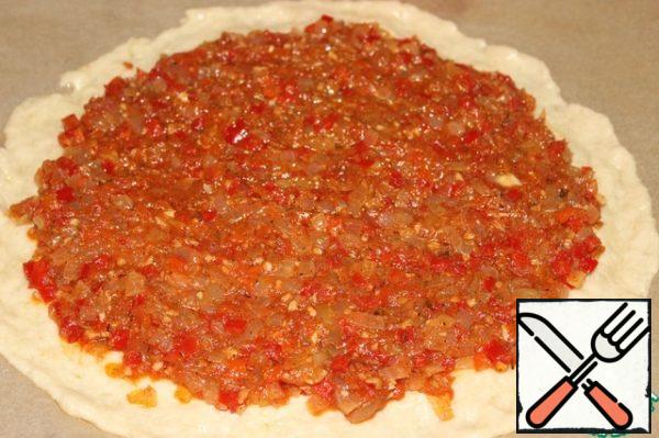 On a baking tray laid with baking paper and mash with your fingers the dough into a circle with a thickness of 3-4 cm.
The edges of the dough knead (width of about 2 cm), so they were thinner than the middle.
Spread the sauce on the dough without going over the edges.