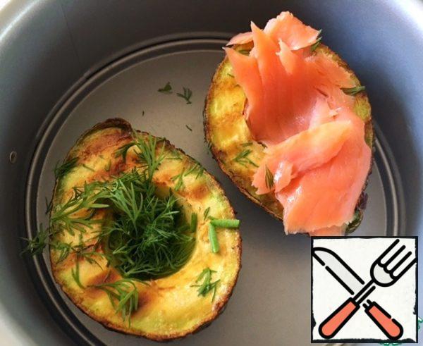 Then transfer the avocado halves to a fireproof mold. Chop the dill and sprinkle the halves.
