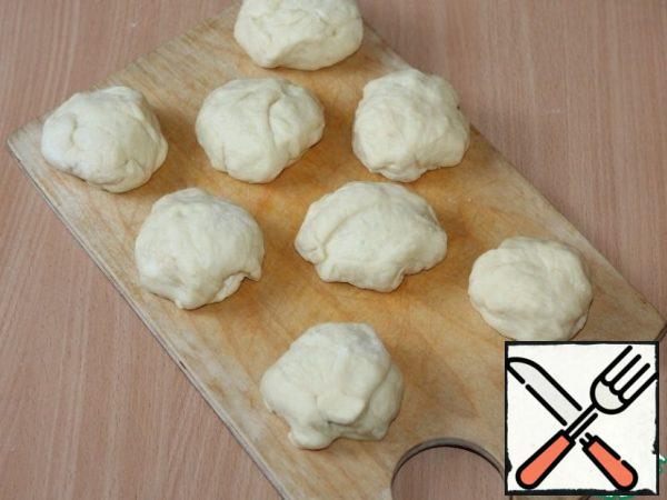 When the dough rises, lubricate your palms with oil, mash it and let it rise.
Sprinkle the countertop with a small amount of flour and form buns, 8 pieces each.
