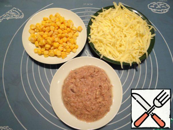 At this time, I prepare the ingredients for the filling - I drain the excess liquid from canned corn and canned fish (if the fish is large pieces, I grind it with a fork), I RUB the cheese on a large grater.