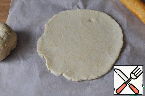 Divide dough in half. Take the baking paper, roll out the dough in a circle 5 mm thick, with a diameter of about 30 cm, there is no need to roll out smoothly.