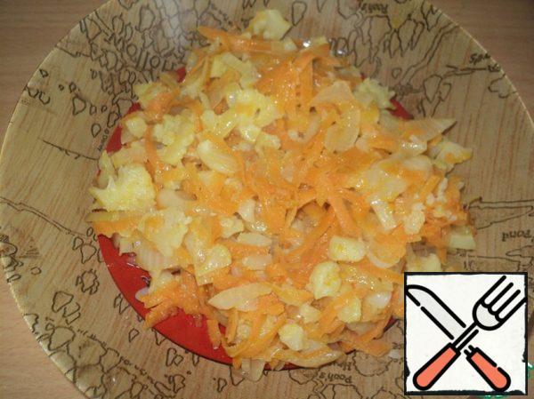 Carrots grate on a coarse grater, onion cut into cubes. Vegetables with cauliflower fry in vegetable oil.
