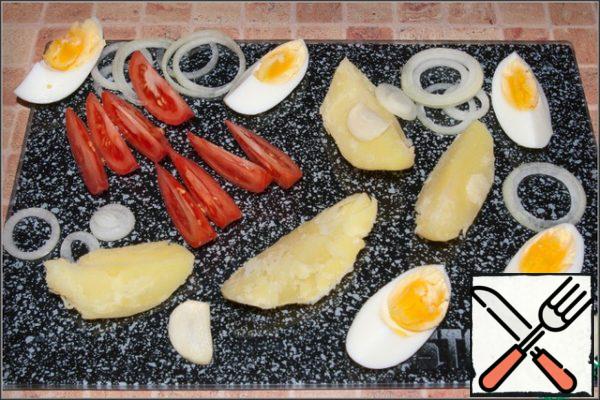 Cooled potatoes, tomatoes and eggs cut into slices, onion - half rings, garlic - plates.