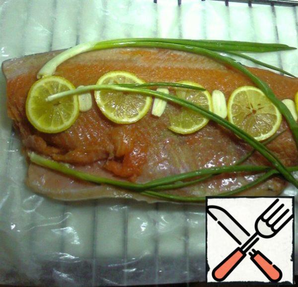 Wet the baking paper - put the trout fillets on it. Season with salt and pepper, add lemon slices and green onions.
