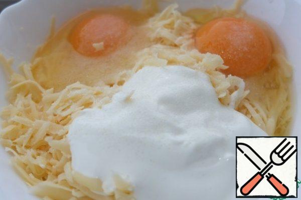 For the filling, grate the cheese on a coarse grater. Add eggs and sour cream. Mix it.