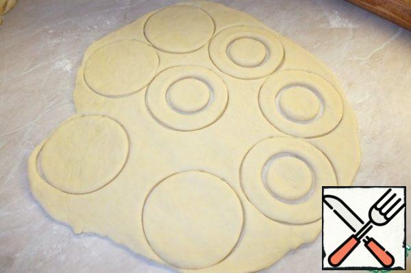 Approached the dough is divided into two parts to make it easier to roll out. On the flour-covered surface, roll out the dough with a thickness of 0.5 cm.
Cut out circles (diameter 8.5 cm), in half of the circles make holes.
