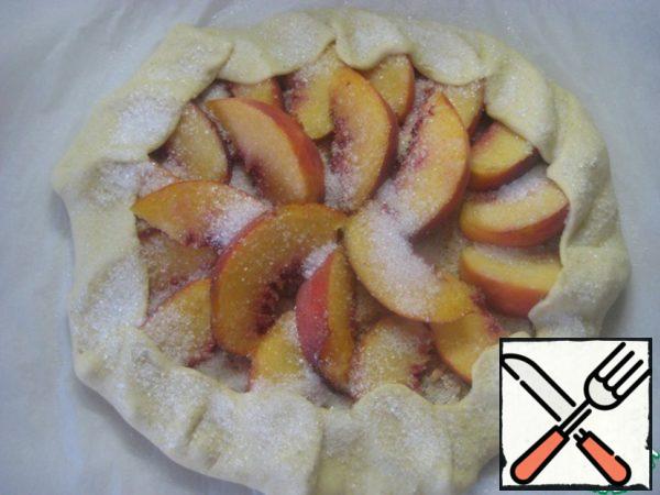 Wrap the edges of the biscuit over the peaches. Lightly sprinkle the edges of the dough with water and sprinkle with sugar.
