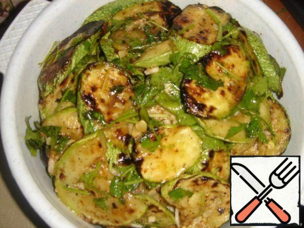 Add chopped greens and garlic to the fried zucchini, season with wine vinegar to taste and mix well. Serve the salad hot.