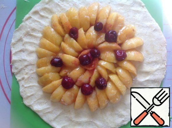 The dough in the center, sprinkle with 1 tsp of starch. Who does not like starch, can sprinkle with crumbled cookies or semolina. Lay out around the apricots and cherries, retreating from the edge of 5-6 cm.