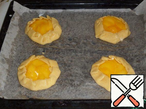 The edges of the dough are applied to the filling, making small "folds". Place the baking sheet in the preheated oven.