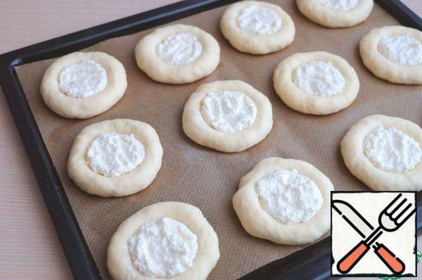 Divide the dough into equal pieces, approximately 65 g. each, formed into round cakes, cover the baking sheet with the scones from the dough with a towel and put the delay on for 15-20 min Then pestle or with bottom of a glass to make the pellets of the recess.