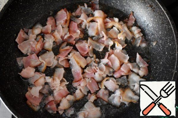 Cut the bacon into pieces and fry in a pan. Grate the cheese.
