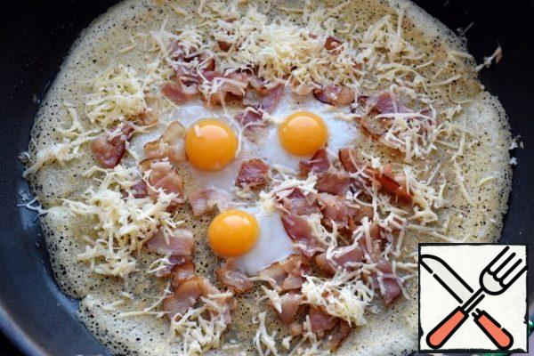 Heat the pan, before frying the first pancake grease with vegetable oil, then grease is not necessary. Spread the dough in a pan, fry the pancake on one side, then turn it over, reduce the heat. On hi, drive quail eggs, distribute bacon and cheese.
