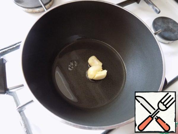 In a saucepan or deep pan pour oil and heat it. Spread a clove of garlic, crushed flat side of the knife and fry it for a minute, so he gave the smell of his oil. It is possible to remove, and can be removed later.