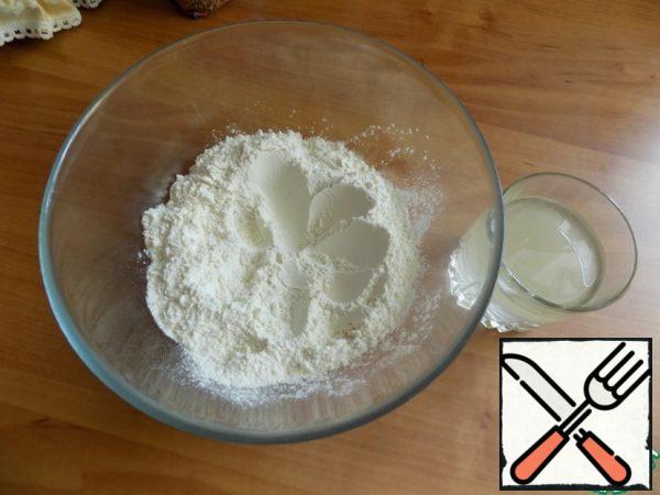 While preparing the filling, I made the dough for biscuits. In the container poured wheat flour and rye, added baking powder, joined. Made a hole in the center. In a glass with a fork connected warm water, sugar, salt and sunflower oil.