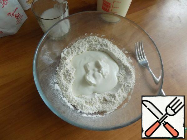 Do deepening and pour homemade kefir. Add sour cream and knead the dough. I first plug clockwise to collect the flour in the mass. Then use your hands to knead the dough.