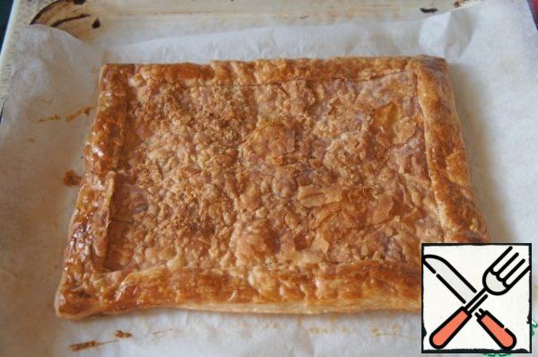 Place the dough on parchment, brush the edges with beaten egg and transfer to a baking sheet. Bake for 15 minutes. Take the pie out of the oven and slightly flatten the middle so that the rim is high.
