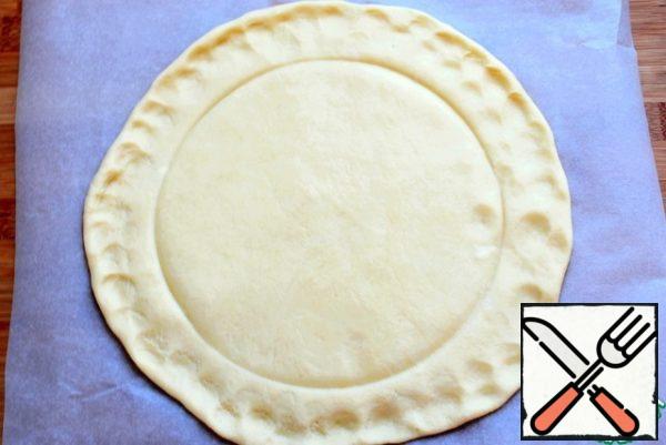 Roll the dough into a circle on parchment paper. Do with plates contour in the middle for ease of placing the filling. remove the dough in the refrigerator for half an hour directly on paper, covering it with a film.