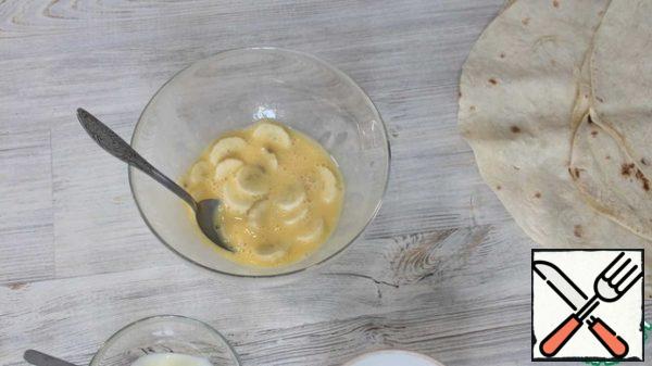 In a bowl, break an egg, mix with condensed milk, banana.
