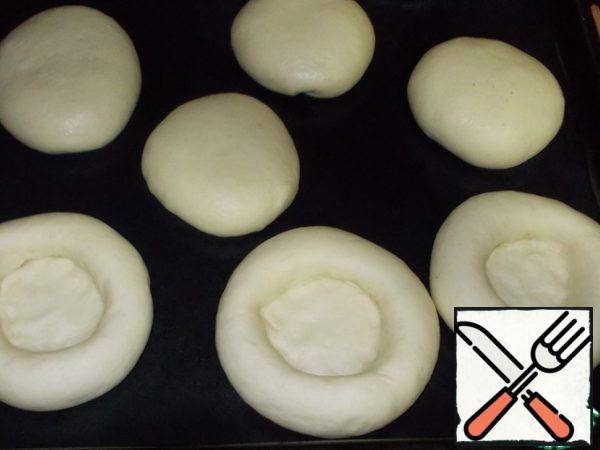 In the center of each piece of dough, make a recess. Some do it with a glass, pressing on the bottom, but I prefer fingers.