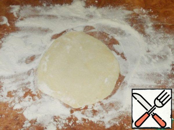 One of the small pieces of dough that were left for decoration, roll out into a thin layer on the table sprinkled with flour.