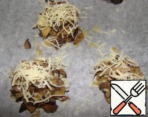 The baking sheet is covered with parchment paper smeared with oil...put a handful of cheese (it is very important that then cheesecakes were removed without difficulty and kept in shape)on the cheese mushrooms...and on top of some more cheese.