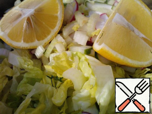 Squeeze the juice of a small lemon into a mixture of vegetables and herbs.
