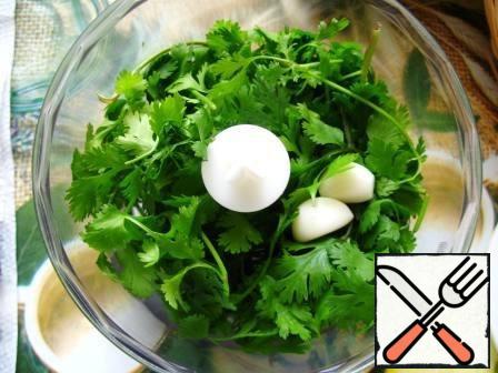 In the bowl of a blender put cilantro with stems. Add a few cloves of garlic.